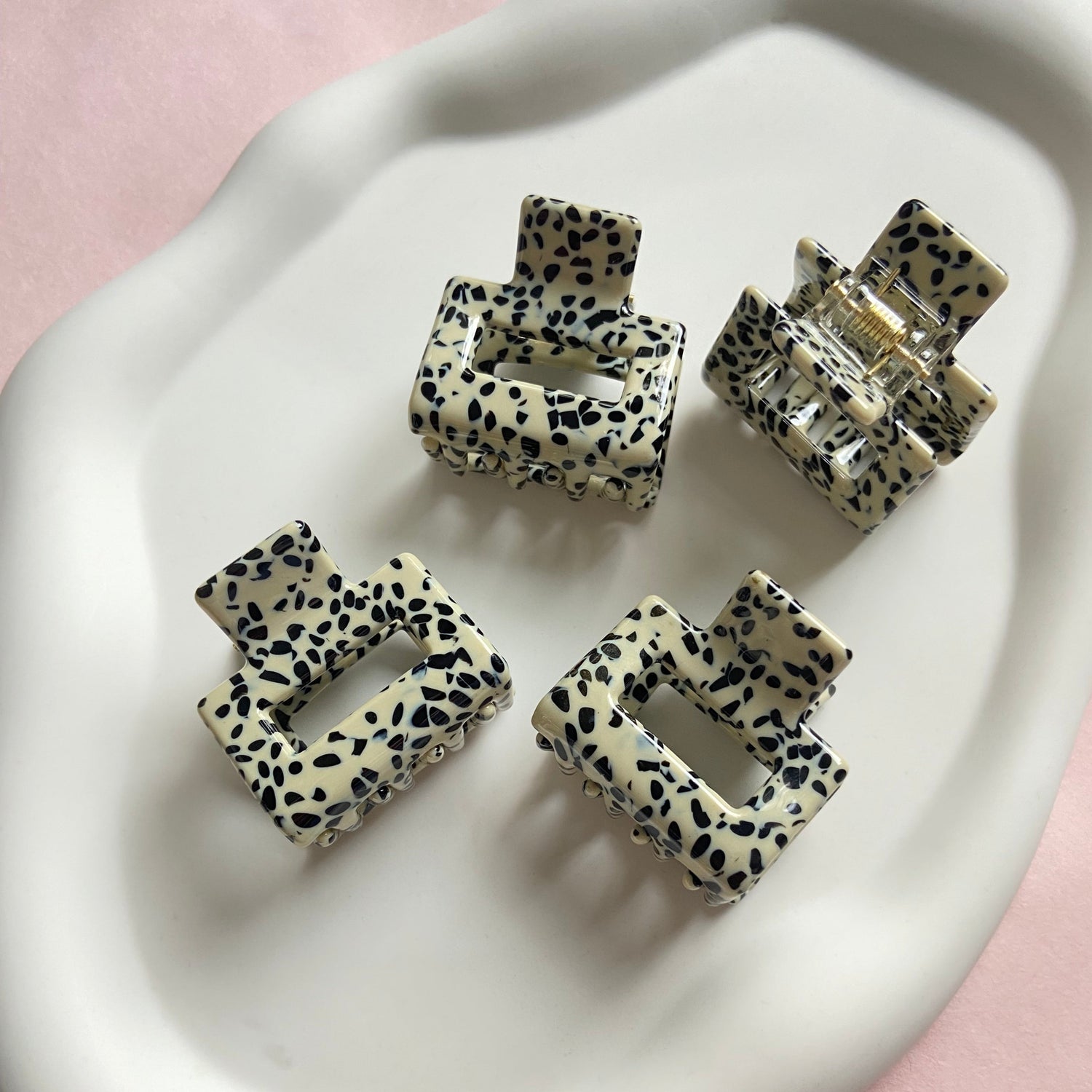 Bild von kleinen Haarklammern in weiss mit schwarzen Punkten in weißer Schale.