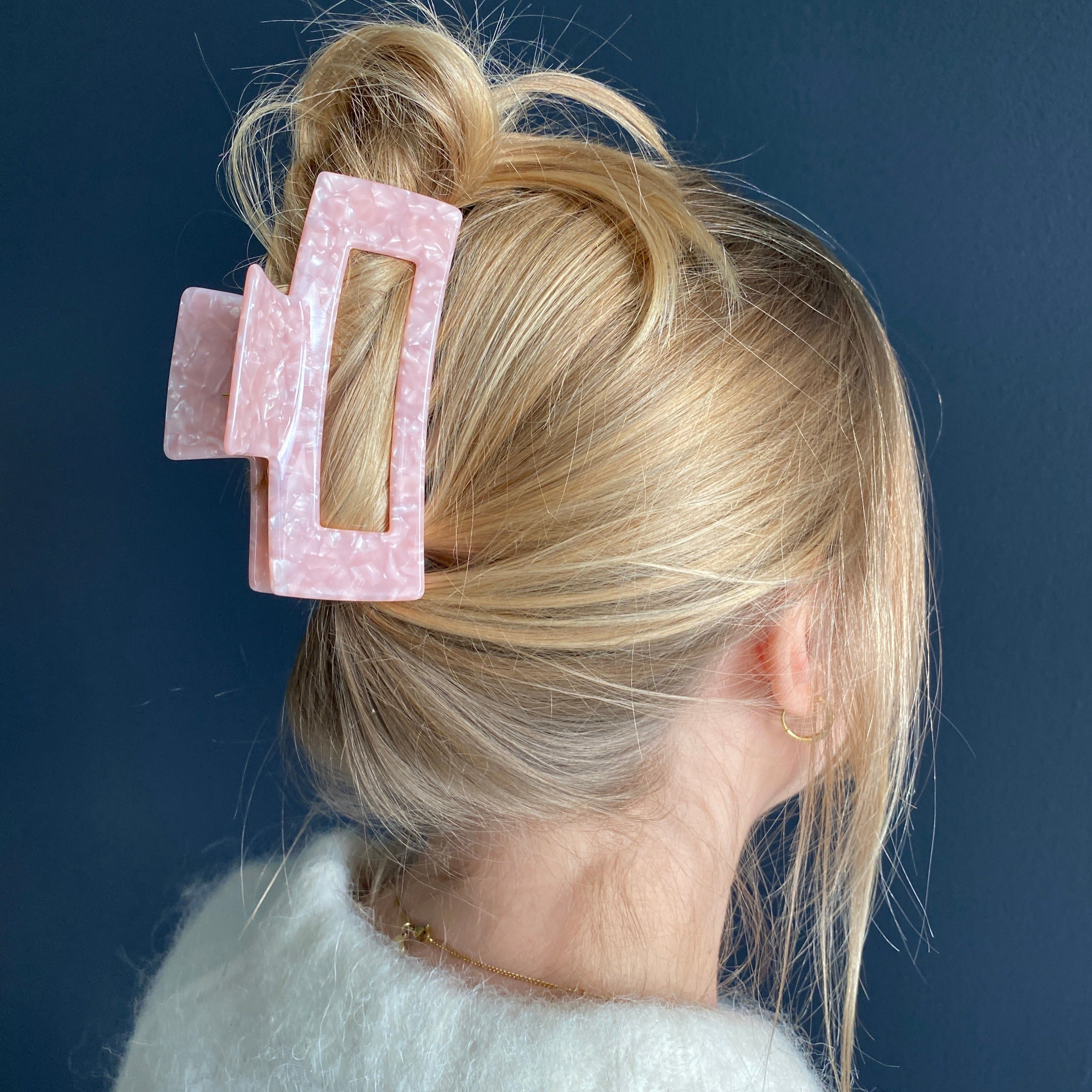 Frau mit am Hinterkopf hochgesteckten Haaren die von einer sehr großen rosa Haarklammer zusammengehalten werden.