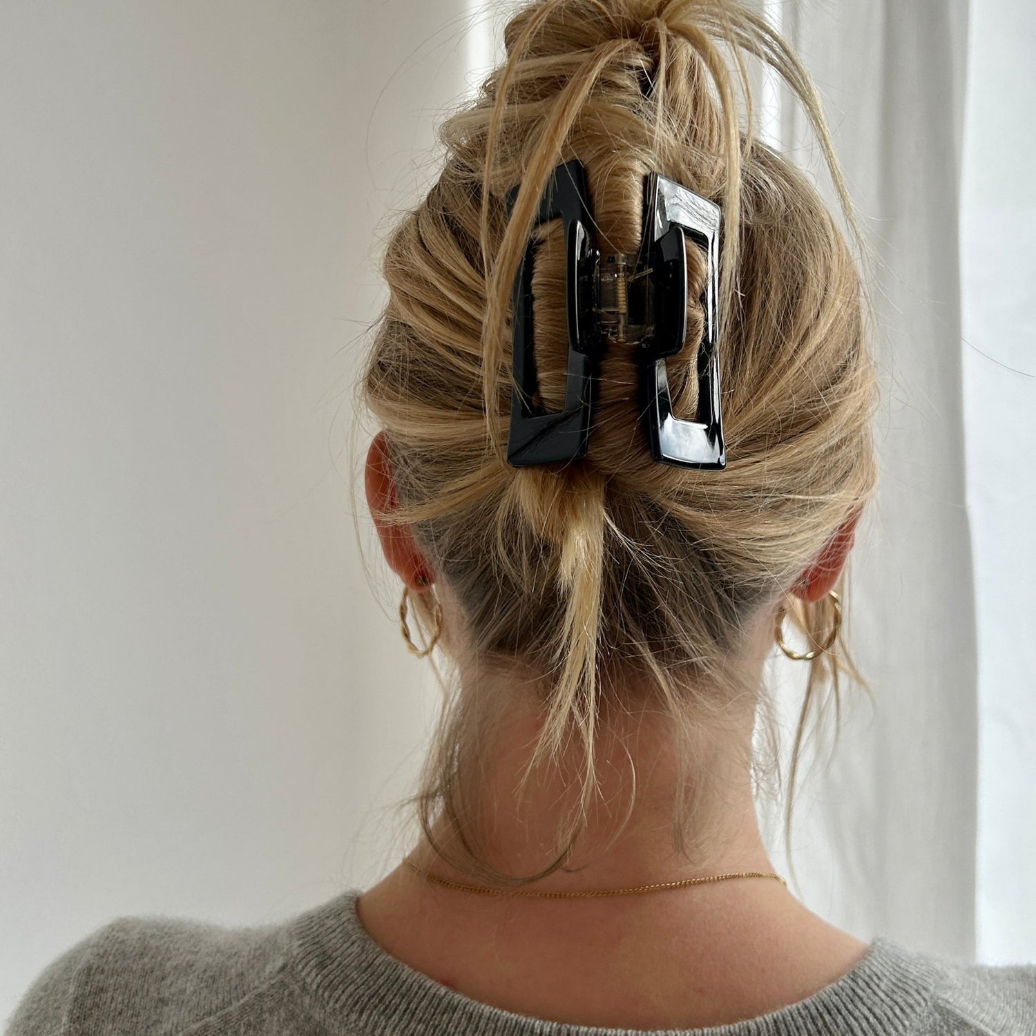 Frau mit langen Haaren die unkompliziert mit einer großen schwarzen Haarklammer hochgesteckt sind