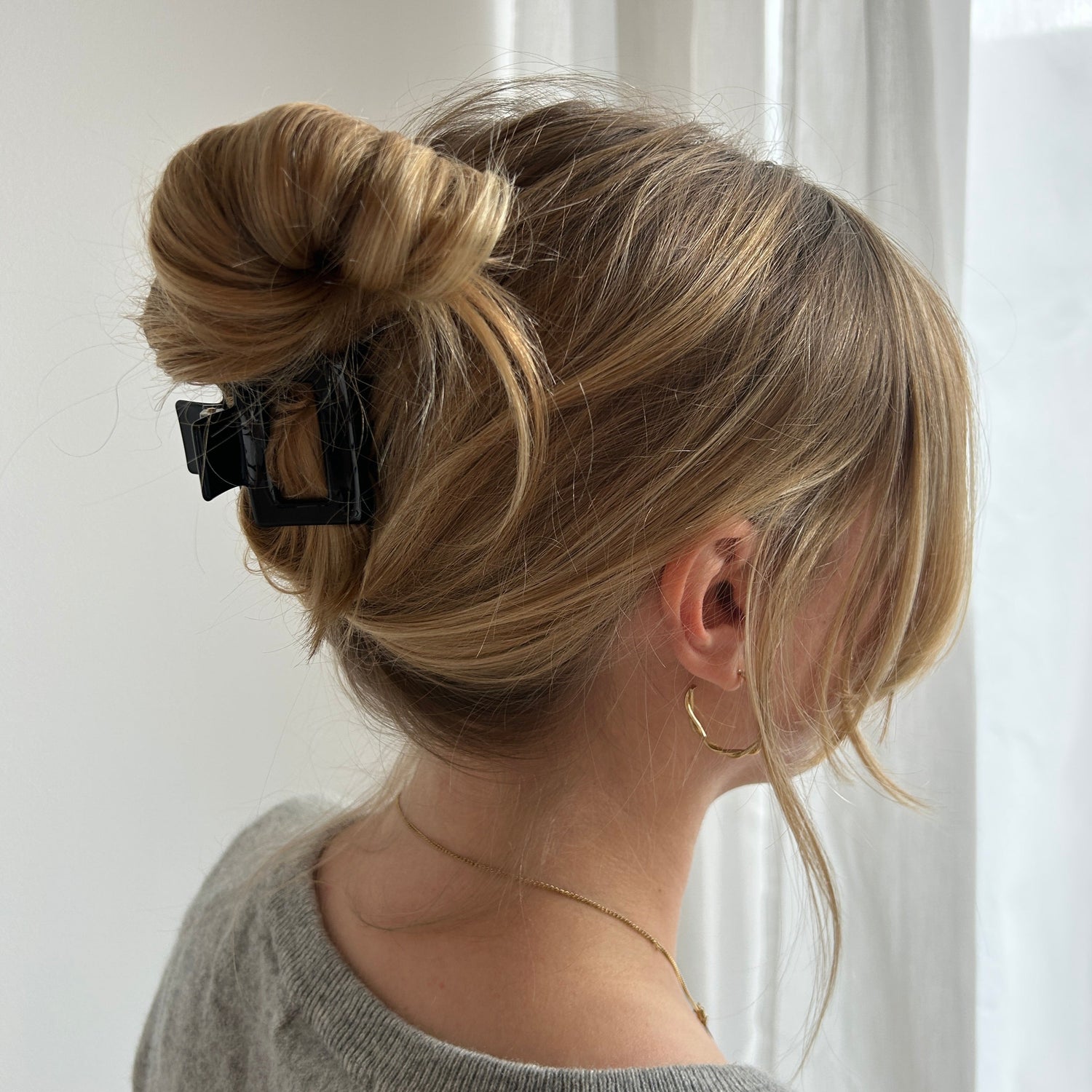 Frau mit lässige hochgesteckten Frisur die durch eine eckige Haarklammer in einfarbigem schwarz gehalten wird.