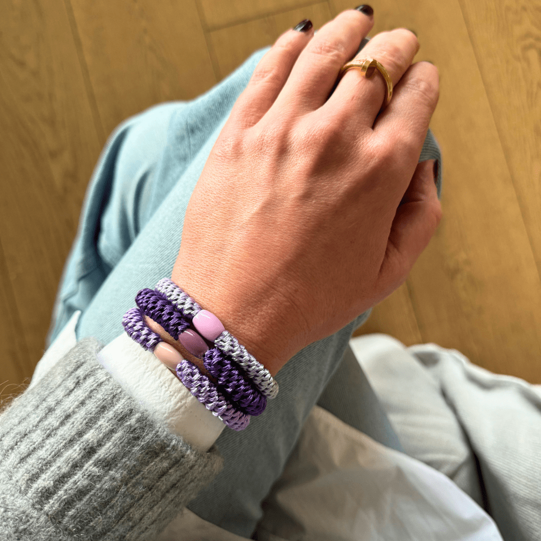 Geflochtene Haargummis im 3er Set von Pizzicato elegant am Handgelenk getragen in Violett und Lila