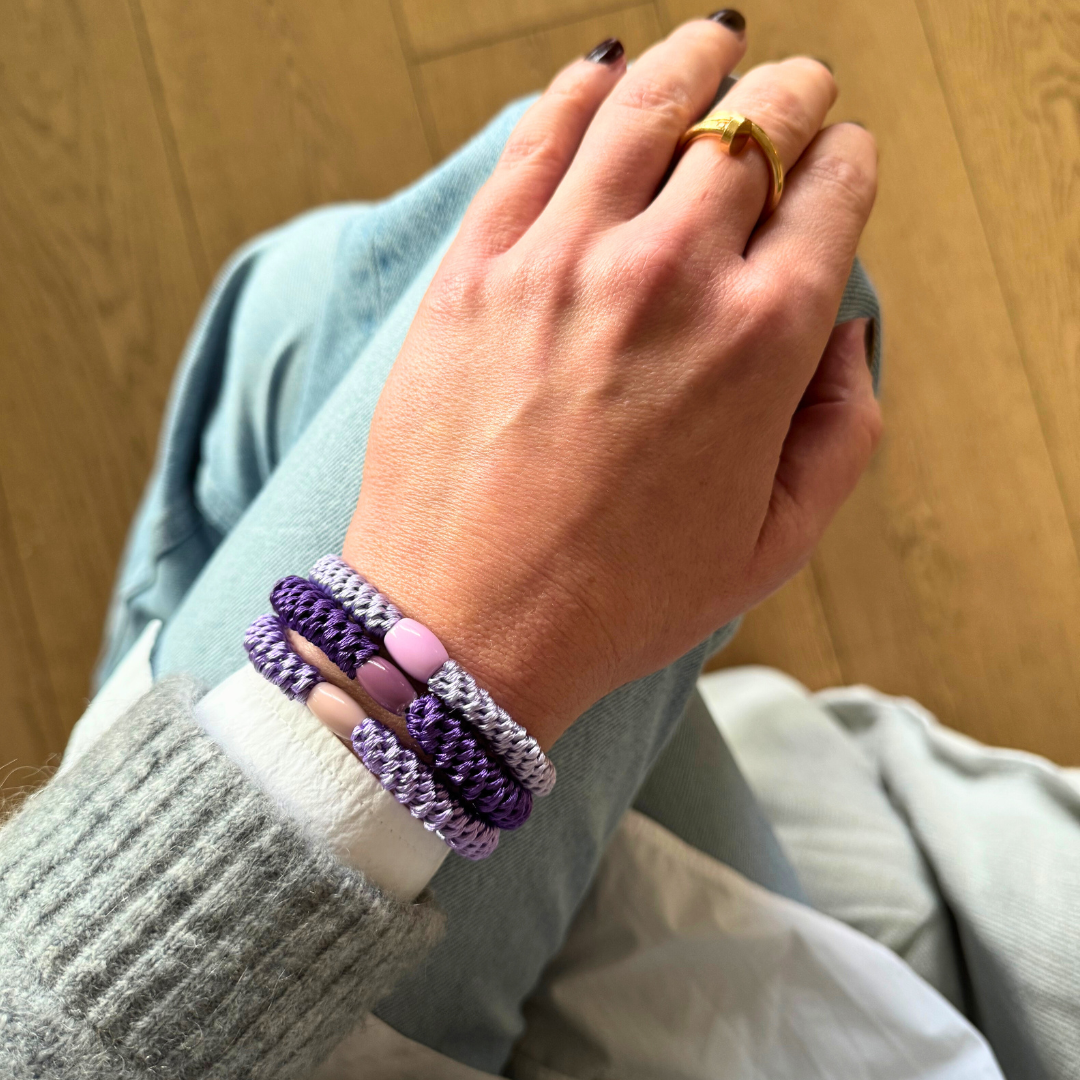 Geflochtene Haargummis im 3er Set von Pizzicato elegant am Handgelenk getragen in Violett und Lila